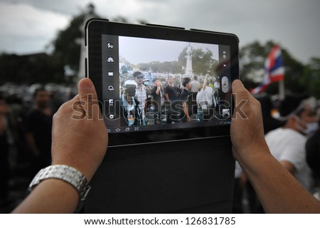 BANGKOK - NOV 24: A protesters uses a tablet computer to photograph an anti-government rally organised by the nationalist Pitak Siam group on Nov 24, 2012 in Bangkok, Thailand.