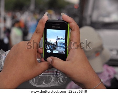 BANGKOK - NOV 24: A protesters uses a smartphone to video an anti-government Pitak Siam rally at Makhawan Bridge on Nov 24, 2012 in Bangkok, Thailand. An estimated 20,000 protesters joined the rally.
