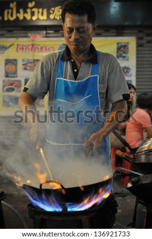BANGKOK - DEC 13: A chef cooks food at a street-side restaurant in Chinatown on Dec 13, 2012 in Bangkok, Thailand. There are 16,000 registered street vendors in Bangkok according to government stats.