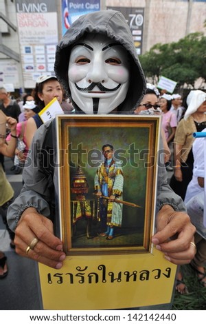 BANGKOK - JUN 9: A protester wearing a Guy Fawkes mask holds a portrait of the Thai king while attending an anti-government rally in Bangkok\'s shopping district on Jun 9, 2013 in Bangkok, Thailand.