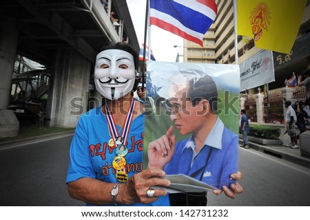 BANGKOK - JUNE 16: A protesters wearing a Guy Fawkes mask and holding a portrait of the Thai king joins an anti-government rally in Bangkok\'s shopping district on June 16, 2013 in Bangkok, Thailand.