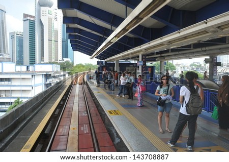 KUALA LUMPUR - MAY 14: Passengers wait on a train station platform of the RapidKL LRT  rail network on May 14, 2013 in Kuala Lumpur, Malaysia. RapidKL transports approximately 690,000 people daily.
