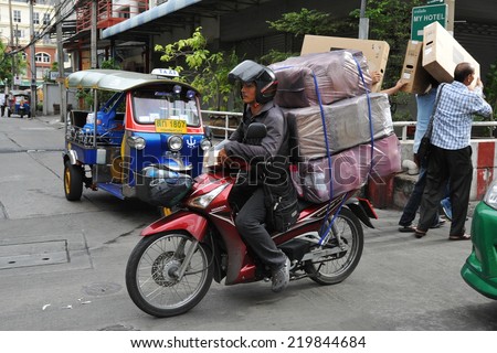 BANGKOK - JUL 8: An unidentified motorcycle courier rides an overloaded bike on a city street on Jul 8, 2013 in Bangkok, Thailand. The use of motorcycles to transport goods is commonplace in Bangkok.