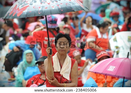 BANGKOK - SEP 15: A woman holds an umbrella at a large Red Shirt rally on Sep 15, 2012 in Bangkok, Thailand. The political rally in the Thai capital marked the 6th anniversary of a military coup.