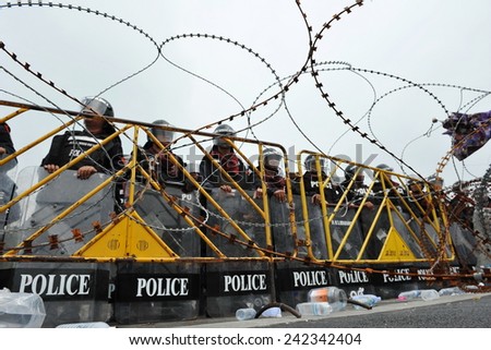 BANGKOK - NOV 24: Riot police stand guard behind razor wire during a violent anti government rally in the Thai capital on Nov 24, 2012 in Bangkok, Thailand.