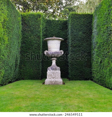 View of an Ornamental Stone Vase, Lush Lawn and Sculpted Hedge Topiary in a Beautiful Garden