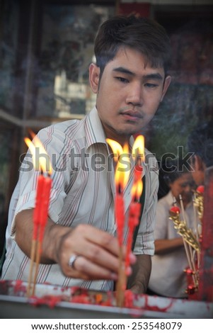 BANGKOK - JAN 30: A temple goer places candles while making merit at a Chinatown Taoist-Buddhist shrine during festivities ushering in the Chinese New Year on Jan 30, 2014 in Bangkok, Thailand.