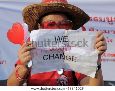 BANGKOK - JANUARY 23: An anti-government red-shirt at a rally at Democracy Monument holds a sign reading \'We Want Change\' on Jaunuary 23, 2011 in Bangkok, Thailand.