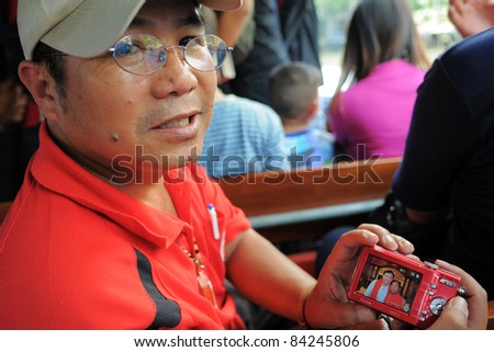 BANGKOK - JAN 23: A red-shirt protester attending an anti-government rally shows a photograph of himself with exiled former Thai Prime Minister Thaksin Shinawatra on Jan 23, 2011 in Bangkok, Thailand.