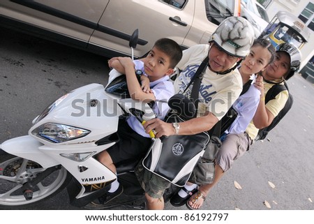BANGKOK - SEPT 12: Unidentified family make a school run by motorbike during evening rush hour on Sept 12, 2011 in Bangkok, Thailand. The use of motorbikes as family transport is commonplace in Thailand.