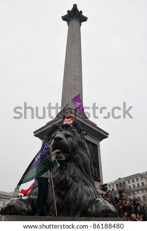 LONDON - MARCH 26: An unidentified protester sits aloft one of the lion statues of Nelson\'s Column in Trafalgar Square during a large anti-cuts rally on March 26, 2011 in London, UK.