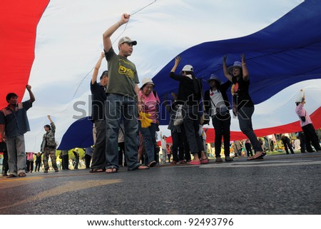 BANGKOK - JAN 25: Nationalist yellow-shirt protesters under a Thai flag near Government House during a large anti-government rally on Jan 25, 2011 in Bangkok, Thailand.