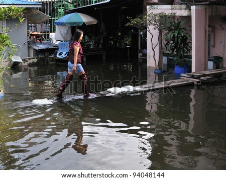 BANGKOK - OCT 26: An unidentified woman walks along a gangplank above floodwater in the city\'s Dusit district as Thailand faces its worst flooding in 50 years on Oct 26, 2011 in Bangkok, Thailand.