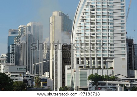 BANGKOK - MAR 5: Smoke rises from Fico Building as firefighters tackle a blaze in the office tower on Mar 5, 2012 in Bangkok, Thailand. The BMA has launched an investigation in the cause of the blaze.