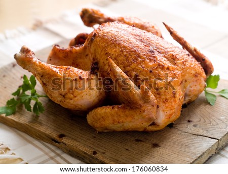 Whole roasted chicken on wooden board, selective focus