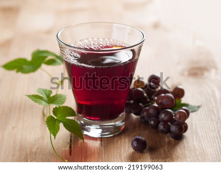 Glass of grape juice with grapes on the background, selective focus