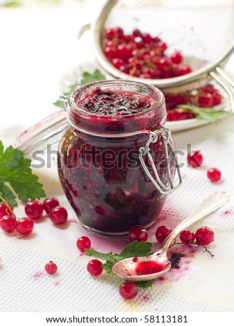 Red currant and black currant jam in jam-jar on dirty towel