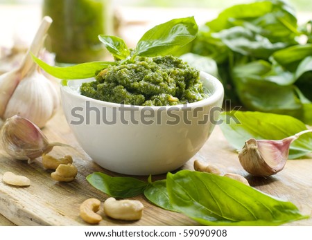 Basil pesto in a small bowl, with fresh basil leaves