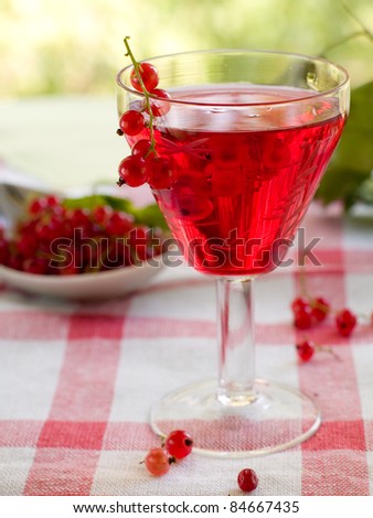 Red currant wine in glass on natural background. Selective focus
