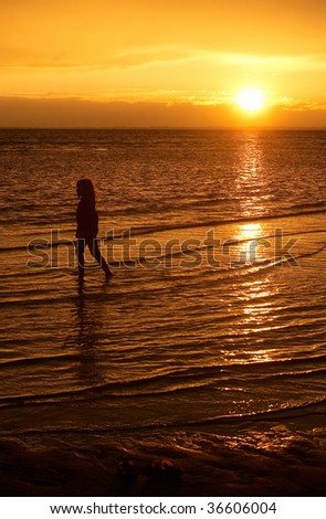 a child paddling in the shallow sea during the sunset after storm