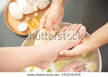 foot washing in spa before treatment. spa treatment and product for female feet and hand spa. white flowers in ceramic bowl with water for aroma therapy at spa.