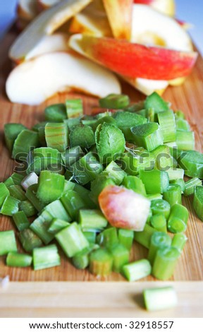 Red apple and green rhubarb cut for compote or jam cooking on a wooden kitchen board