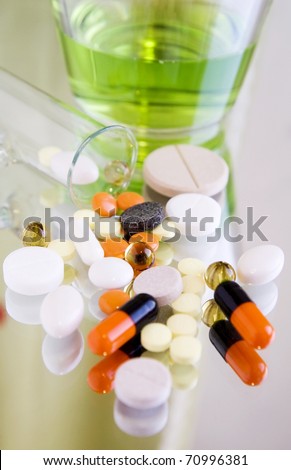Different colorful pills and medicines on a mirror surface, close up, blur background, vertical