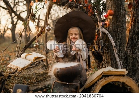 Happy Halloween. A cute girl in a witch costume is in the witch's den. Cute cheerful little witch brews a magic potion. Halloween. Photo stock © 