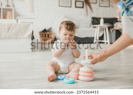 Similar – Image, Stock Photo 6 month old baby playing wearing black and white playing with colorful ring stack toy