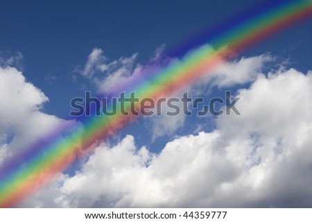 Blue sky with clouds. Rainbow in front.