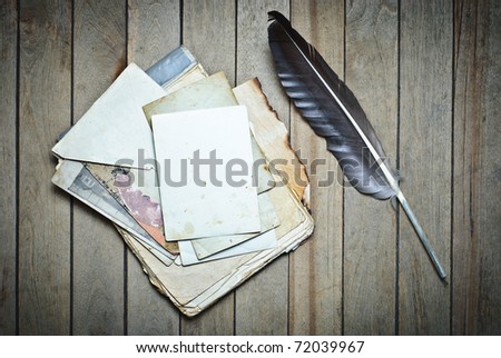 Vintage notebook with old papers and feather on a wooden table