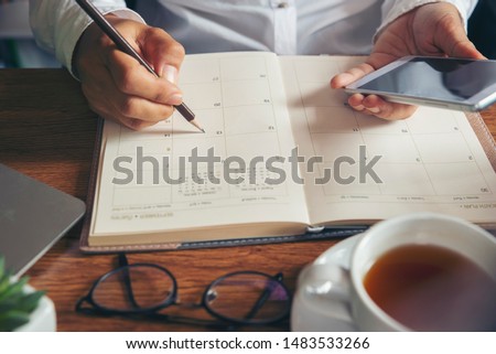 Planner plan Schedule Calendar and reminder agenda, work online at home. Women hand planning daily appointment and note holiday trip in diary at office desk. 2022 Calendar reminder event concept.