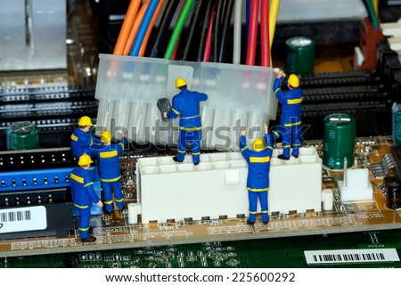 Miniature construction worker figurines posed as if working on a computer motherboard.