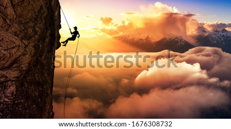 Silhouette Rappelling from Cliff. Beautiful aerial view of the mountains during a colorful and vibrant sunset or sunrise. Landscape taken in British Columbia, Canada. composite. Concept: Adventure Сток-фото © 