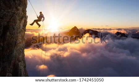 Epic Adventurous Extreme Sport Composite of Rock Climbing Man Rappelling from a Cliff. Mountain Landscape Background from British Columbia, Canada. Concept: Explore, Hike, Adventure, Lifestyle