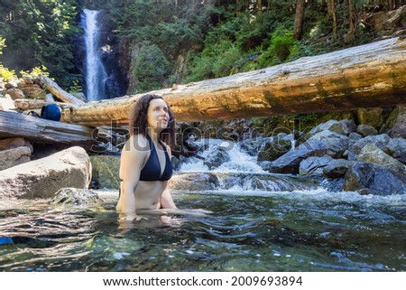 Adult Caucasian Woman hiker swimming in glacier water at Norvan Falls during hot and sunny summer day. Canadian Nature Background. Lynn Valley, North Vancouver, British Columbia, Canada. Stok fotoğraf © 