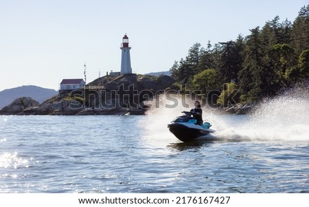 Adventurous Caucasian Woman on water scooter riding in the Ocean. Lighthouse park in background. West Vancouver, British Columbia, Canada. Foto stock © 