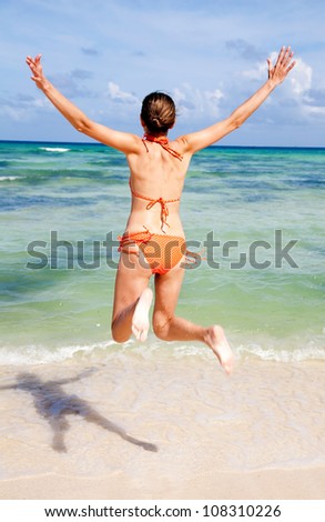 Back view of slim woman jumping on the sea