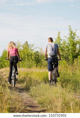 Back view of sporty couple riding bicycles  in the forest