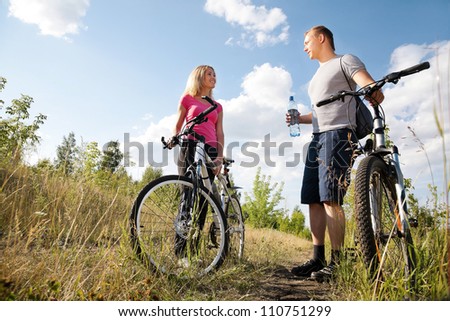 Attractive couple walking after biking and drinking water in the forest