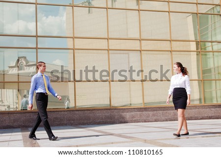 Two businesspeople walking to meet each other near the office building