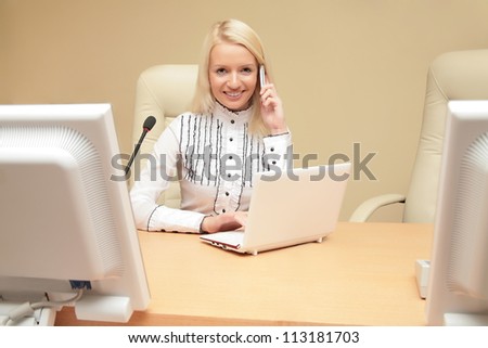 Businesswoman speaking on her cell phone and working on her laptop
