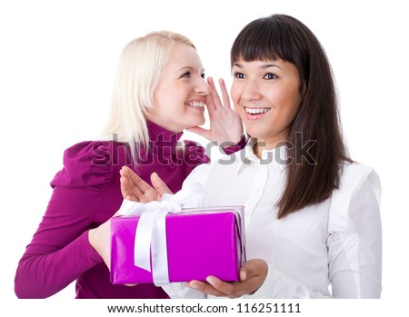 Young woman gives a gift to her friend whispering something in her ear