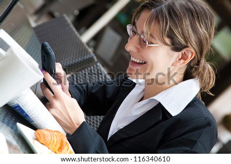 Smiling businesswoman using her cell phone in the cafe