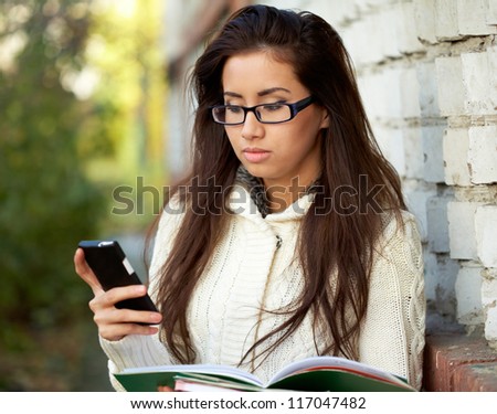 Female student with her copybooks and cell-phone
