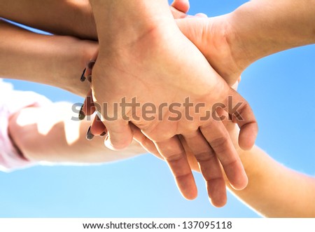 Team of people hands on top of each other over blue sky