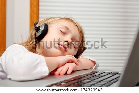 Cute little girl in headphone  sleeping on laptop