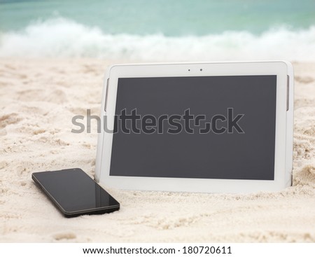 Digital tablet computer and smartphone on ocean beach