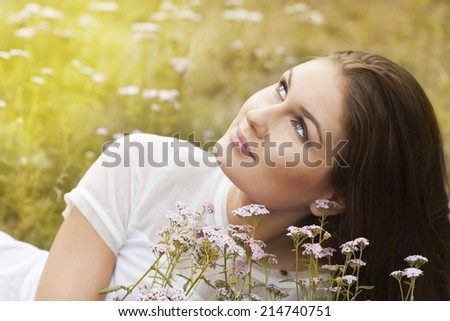 Beautiful Model young Woman with long hair on a Field Smiling. Cute Teenage Girl Lying on the Field