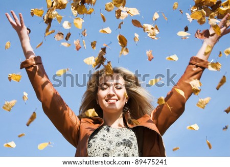 Attractive woman throw up autumnal leaves